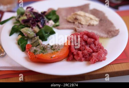 Eine köstliche Vorspeise aus Piedmont. Steak Tartare, Carpaccio, gefüllte Paprika und Salat Stockfoto