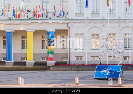 Logo und Flaggen von NATO-Mitgliedern in der Nähe des Präsidentenpalastes, die zusammen mit der Flagge der Ukraine während des NATO-Gipfels 2023 im Zentrum von Vilnius winkten Stockfoto