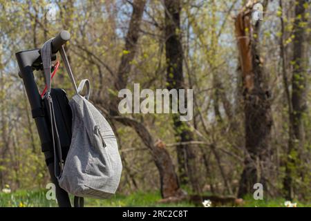 Grauer Urban Rucksack wiegt auf einem elektrischen Roller im Sommer auf der Straße in der Sonne in der Stadt, Lifestyle, Stadtverkehr und Mode Stockfoto