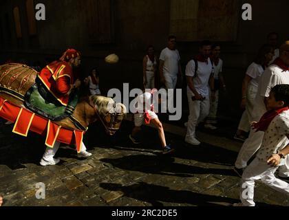 Pamplona, Spanien, Donnerstag, 11. Juli 2023. Ein 'Zaldiko' schlägt ein Mädchen, wenn er an der täglichen Parade der gigantes y Cabezudos (Parade der Riesen und Großköpfe) des San Fermin Festivals in teilnimmt. Zaldikos sind traditionelle Charaktere, die auf Papppferden reiten, die durch die Straßen ziehen und Zuschauer mit einem Schwamm treffen, der an einen Stock gebunden ist. Kredit: Mikel Cia Da Riva/Alamy Live News Stockfoto