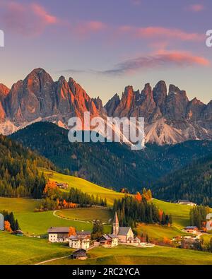 Ein vertikales 4:5-Bild von einem herbstlichen Sonnenuntergang in der berühmten Kirche und dem Dorf Santa Maddalena vor den Berggipfeln Geisler/Dolomiten Stockfoto