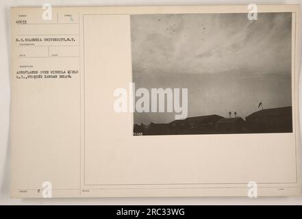 Ein Foto, das Flugzeuge zeigt, die über Mineola Field in Long Island, New York fliegen. Der Hangar trägt die Nummer 46633 und gehört zur South Carolina Einheit der Columbia University. Das Bild wurde von einem Fotografen aufgenommen und hat eine Beschreibung, in der „Flugzeuge über Mineola Field“ mit zusätzlichen Notizen erwähnt wird, die den Hangar und das zugewiesene Symbol erwähnen. Stockfoto