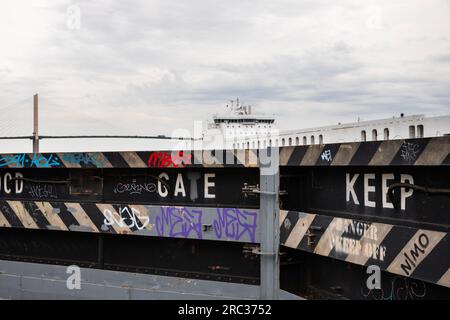 Hochwasser-Verteidigungstor entlang der Themse Mündung, Thurrock, Essex, mit Schiff und Queen Elizabeth II Dartford Crossing Bridge im Hintergrund. Stockfoto