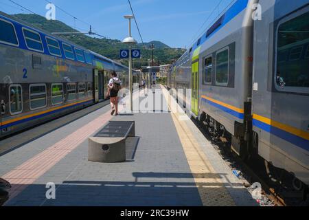 Juni 2023 La Spezia, Italien: Bahnhof, Passagiere mit Koffer und Schnellzüge durch die Berglandschaft Stockfoto