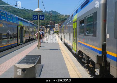 Juni 2023 La Spezia, Italien: Bahnhof, Passagiere mit Koffer und Schnellzüge durch die Berglandschaft Stockfoto