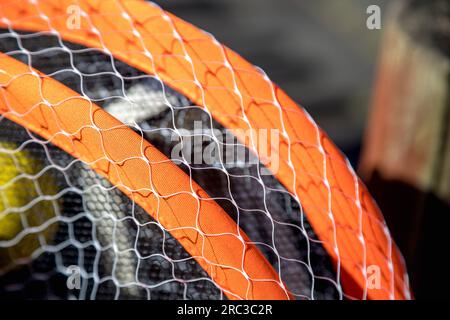 Detailbild von Tennisschlägern und Ball auf einem sehr verschwommenen Hintergrund, an einem sehr sonnigen Tag. Geringe Schärfentiefe. Wunderschöner Kontrast der Texturen. Stockfoto