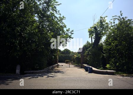 Tor am Eingang eines Herrenhauses, vom Rand einer Straße in der italienischen Landschaft aus gesehen Stockfoto