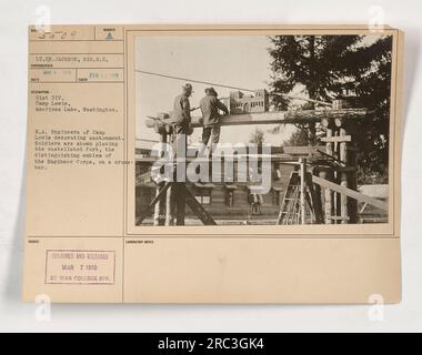 Amerikanische Soldaten aus der 91. Division im Camp Lewis in American Lake, Washington, werden dabei gesehen, wie sie das Kantonment schmücken, indem sie die kastellierte Festung, das Symbol des Ingenieurkorps, an einer Querstange platzieren. Das Foto wurde von Lieutenant Fähnrich Jackson, Signal Reserve Corps, im März 1918 aufgenommen. Stockfoto