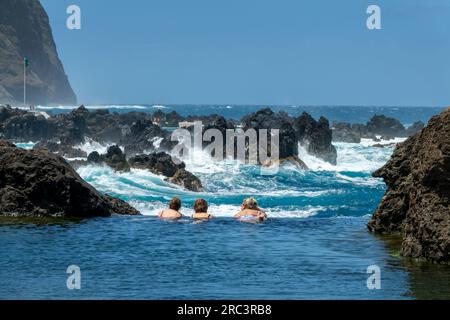 Touristen schwimmen in den natürlichen Meerwasser-Lava-Pools in Porto Moniz, Insel Madeira, Portugal Stockfoto