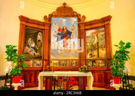 Guadalest, Alicante, Spanien - 14. Januar 2023: Kircheninnere mit Bänken, die zum Altar führen. Die Bänke sind aus Holz. Stockfoto