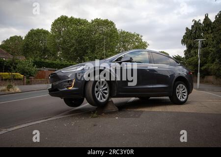 Tesla sitzt fest, nachdem er versehentlich über einen Poller an der Ecke einer Wohnstraße in South Wimbledon, London, England, gefahren ist Stockfoto