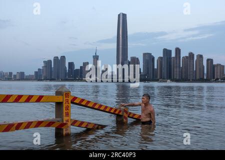 Wuhan, China. 11. Juli 2023. Ein Mann kühlt sich im Jangtse in Wuhan, in Chinas zentraler Provinz Hubei, ab. Der 11. Juli markiert den Beginn der traditionell als Chinas 40-tägige heiße und feuchte Jahreszeit, den Hundetagen des Sommers, bekannten Zeit. Am Dienstag verlängerte das National Meteorological Center eine orangefarbene Alarmstufe - die zweithöchste Alarmstufe - für hohe Temperaturen, während Hitzewellen riesige Teile des Landes verbrennen. Kredit: SOPA Images Limited/Alamy Live News Stockfoto