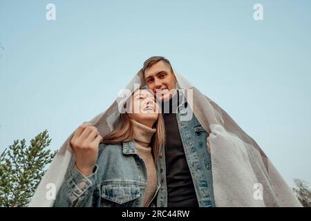 Ein junges Paar ist mit einem Karo in Form eines Hausdachs bedeckt. Hauskonzept Stockfoto