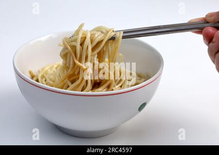 Einfache Instantnudeln ohne Belag mit schwarzer Schüssel auf weißem Hintergrund isoliert mit Schneideweg. Asiatisches und chinesisches Fast-Food-Konzept. Stockfoto