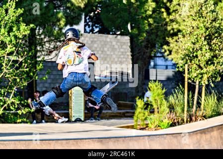 Igualada, Barcelona; 28. Juni 2023: Junger Mann, der Scooter (Freestyle Scooter) im neuen Skatepark des zentralen Parks von Igualada, Barce, praktiziert Stockfoto