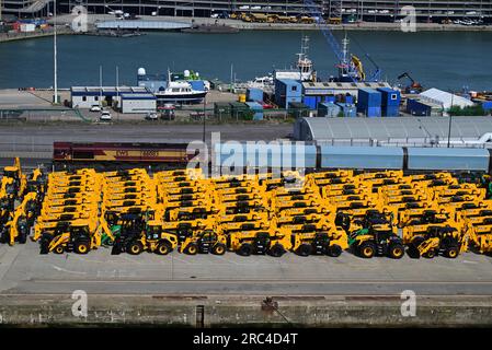 EWS Klasse 66 dieselelektrische Güterlokomotive Nr. 66083, die einen Autoträgerzug an den Southampton Docks steuert, mit gelben JCB's am Kai. Stockfoto