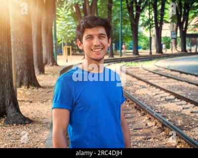 Drei Vierteldrehungen von einem gutaussehenden jungen Mann in der Stadt, der ein blaues Polo-Shirt trägt und in die Kamera lächelt Stockfoto