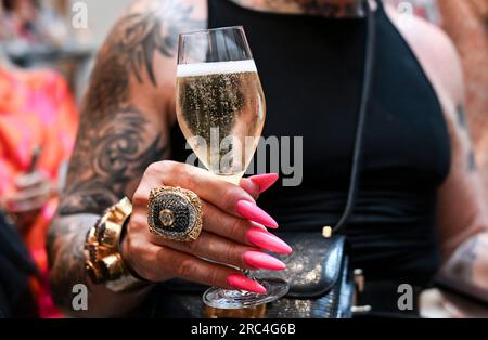 Berlin, Deutschland. 12. Juli 2023. Der Designer Harald Glööckler serviert während der Berliner Modewoche ein Glas Champagner bei der Show von Anja Gockel im Hotel Adlon. Kredit: Jens Kalaene/dpa/Alamy Live News Stockfoto