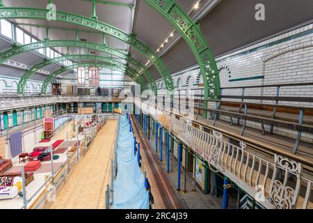 Birmingham, Großbritannien. 12. Juli 2023. Ein Swimmingpool aus dem Jahr 1907 ist die Heimat einer vorübergehenden Umwandlung in ein Wohnzimmer. Das Balsall Heath Gala Pool in der Innenstadt von Balsall Heath, Birmingham, bietet Kunstwerke, Teppiche und weiche Möbel, die einen willkommenen Ort für eine Tasse Tee und ein Gespräch bieten. Die Bäder der Moseley Road werden zur gleichen Zeit renoviert, um ihre edwardianischen Armaturen und Armaturen zu präsentieren. Kredit: Peter Lopeman/Alamy Live News Stockfoto