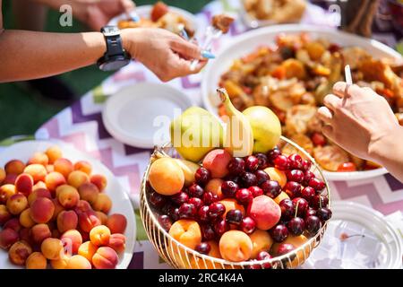 Buffet im Freien. Frisches Obst und traditionelle usbekische Küche. Dimlama: Gedünstetes Gemüse mit Fleisch in einem großen zentralasiatischen Kessel. Stockfoto