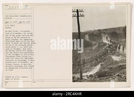 Die amerikanische Division kehrt aus der Hilfsaktion zurück und überquert eine Straße in der Nähe von Le Morthomme, 5 km nördlich von Grandpre, Ardennen, Frankreich. Im Hintergrund eine Brücke und 40 cm. Die Spurlinie, die von den zurückziehenden Deutschen in die Luft gesprengt wurde, ist zu sehen. Der Hügel nördlich und östlich von Grandpre ist voller amerikanischer und deutscher Gräber, die als Erinnerung an den intensiven Kampf in der Gegend dienen. Stockfoto