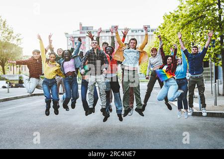 Gruppe glücklicher, multiethnischer junger Erwachsener im Alter von 18-20 Jahren, die mit erhobenen Händen auf der Straße lächeln Stockfoto