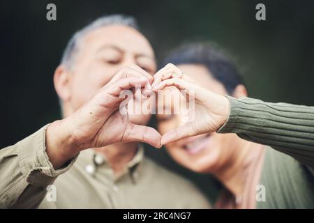 Herz, Hände und ein Seniorenpaar in einem Haus aus Liebe, Fürsorge und Emoji zusammen. Glücklich, vertrauensvoll und ein älterer Mann und eine ältere Frau mit einer Geste für Stockfoto