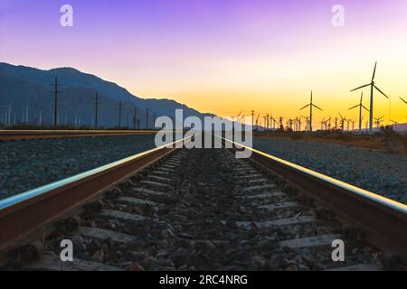 Ein atemberaubender Sonnenuntergang über den Yuma Subdivision Tracks von Union Pacific, der parallel zu den Windmühlen von Palm Springs nordwestlich verläuft. Stockfoto