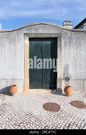 Europa, Portugal, Alentejo Region, Golega, große grüne Eingangstür durch Mauer zur Rua Joao de Deus Stockfoto