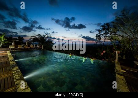 Malerischer Blick auf den Swimmingpool mit klarem Wasser und Lichter des tropischen Resorts in Madagaskar mit unbekannten Schwimmern gegen blauen Himmel mit Wolken Stockfoto