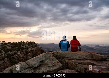 Rückblick auf nicht wiedererkennbare Touristen, die auf einem felsigen Hügel sitzen und die malerische Landschaft in Valencia bewundern und wegzeigen Stockfoto