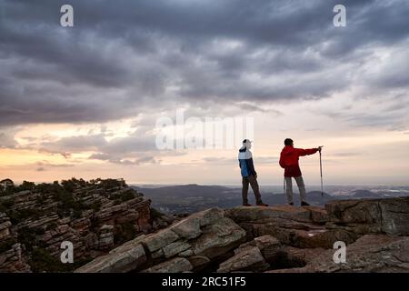 Rückblick auf Touristen auf dem felsigen Hügel mit nordischen Stöcken, bewundern die malerische Landschaft in Valencia und zeigen weg Stockfoto