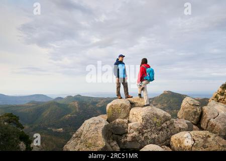 Seitenansicht der Frau mit Rucksack, die mit ihrem Mann auf dem Gipfel des Berges steht und die majestätische Landschaft des Hochlands in Spanien genießt Stockfoto