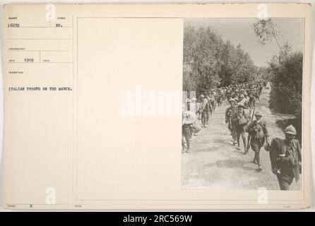 Italienische Truppen marschierten 1919. Dieses Foto zeigt Soldaten, die während des Ersten Weltkriegs unterwegs waren. Die Soldaten werden in Formation gesehen und symbolisieren militärische Disziplin. Das Bild bietet einen Einblick in die Aktivitäten der italienischen Truppen während dieser Zeit. Anmerkung: Das ist Foto Nummer 16032, aufgenommen von dem Fotografen RECO. Stockfoto