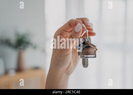 Die Frau hält Hausschlüssel und symbolisiert ein neues Zuhause. Immobilienmakler bietet Wohnungen zum Verkauf oder zur Miete an. Hypothekenanzeige. Stockfoto