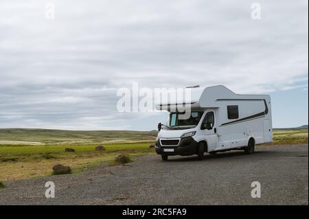 Wunderschöne Natur in Island. Malerische isländische Landschaft an bewölkten Tagen. Moderner Wohnwagen auf Asphaltparkplatz. Reisen im mobilen Zuhause Stockfoto