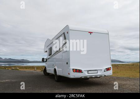 Wunderschöne Natur in Island. Malerische isländische Landschaft an bewölkten Tagen. Moderner Wohnwagen auf Asphaltparkplatz. Reisen im mobilen Zuhause Stockfoto