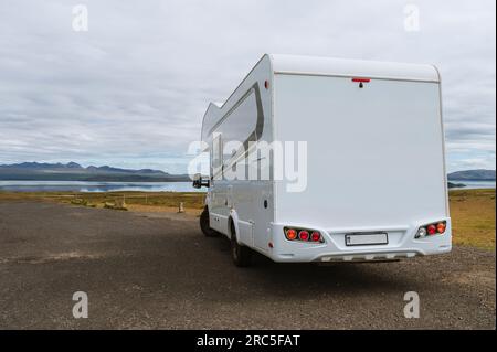 Wunderschöne Natur in Island. Malerische isländische Landschaft an bewölkten Tagen. Moderner Wohnwagen auf Asphaltparkplatz. Reisen im mobilen Zuhause Stockfoto