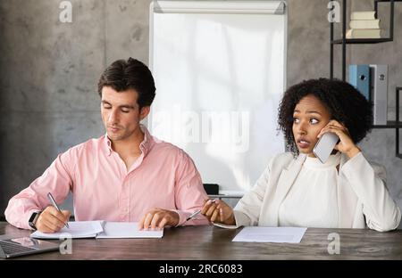 Multiethnische Kollegen, die am Schreibtisch sitzen und an einem Projekt arbeiten Stockfoto