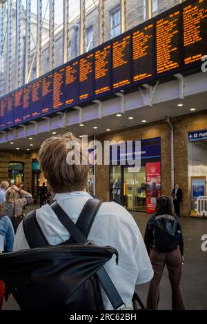 Der Rail Commuter sieht die Abfahrtsschilder an der Londoner Kings Cross Station. Der Pendler wartet am Bahnhof Kings Cross in London auf einen Zug. Stockfoto