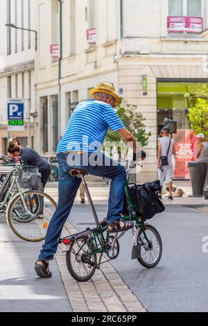 Älterer Franzose auf einem englischen Brompton A-Line Klappfahrrad im Stadtzentrum - Tours, Indre-et-Loire (37), Frankreich. Stockfoto