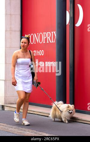 Junge Frau in weißem trägerlosem Kleid, die mit ihrem Hund incity Center - Tours, Indre-et-Loire (37), Frankreich spaziert. Stockfoto