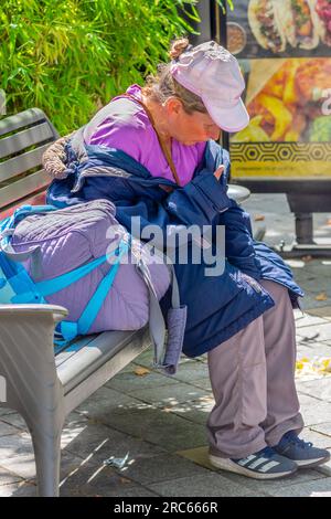 Obdachlose Frau, die auf einer Bank im Stadtzentrum sitzt und ihre Sachen dabei hat - Tours, Indre-et-Loire (37), Frankreich. Stockfoto