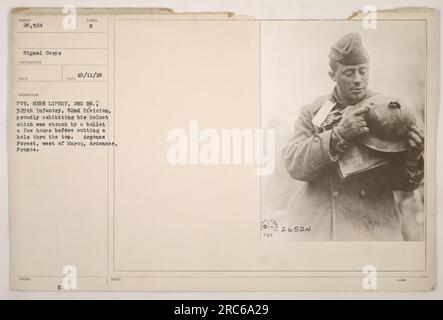 Private Mere Lipsky, aus dem 2. Bataillon der 329. Infanterie in der 82. Division, zeigt seinen Helm, der von einer Kugel durchstochen wurde und ein Loch oben hinterlässt. Der Vorfall ereignete sich im Argonne-Wald westlich von Maroq in der Ardennen-Region Frankreichs. Das Foto wurde am 11. Oktober 1918 aufgenommen. Stockfoto