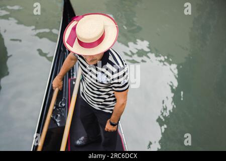 Gondoliere mit Gondolierhut auf einer Gondel, die in Venedig, Italien rudert Stockfoto