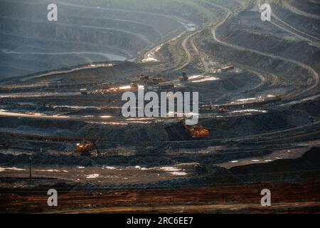 Hydraulikbagger und Kipplaster, die im Tagebau in Bergbau- und Verarbeitungsanlagen Erdbewegungsarbeiten durchführen. Stockfoto