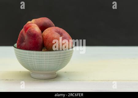 Eine blaue Porzellanschüssel mit Paraguayanfrüchten auf hell bemalten Holzplanken Stockfoto