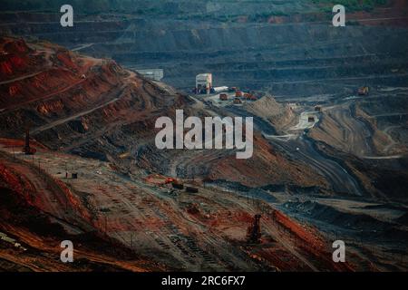 Hydraulikbagger und Kipplaster, die im Tagebau in Bergbau- und Verarbeitungsanlagen Erdbewegungsarbeiten durchführen. Stockfoto