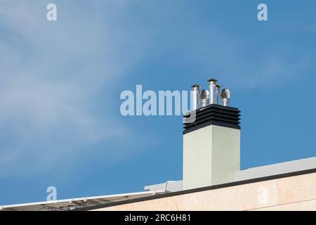 Kaminkappen aus Edelstahl auf dem Dach mit blauem Himmel Stockfoto