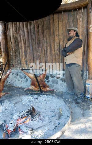 Argentinischer Gaucho, der Lamm über einem offenen Feuer in Südpatagonien, Argentinien, brät Stockfoto